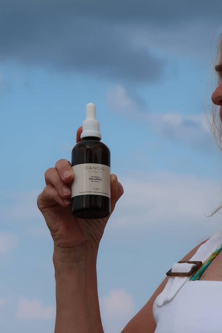 En model holder DANOIS' Plantebaseret Collagen, baggrunden er en smuk blå himmel